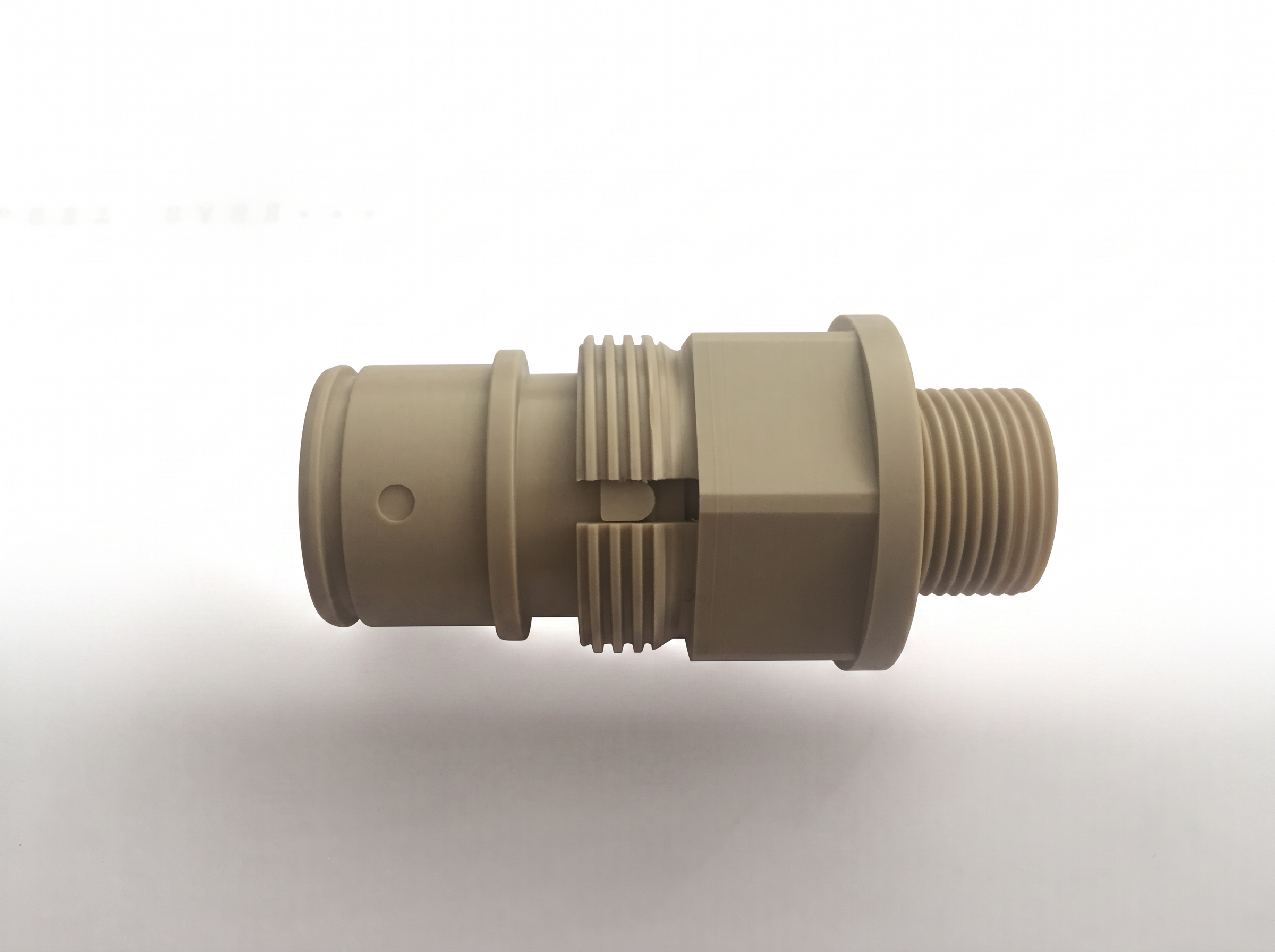 Tan PEEK machined connector with threaded sections and hexagonal body